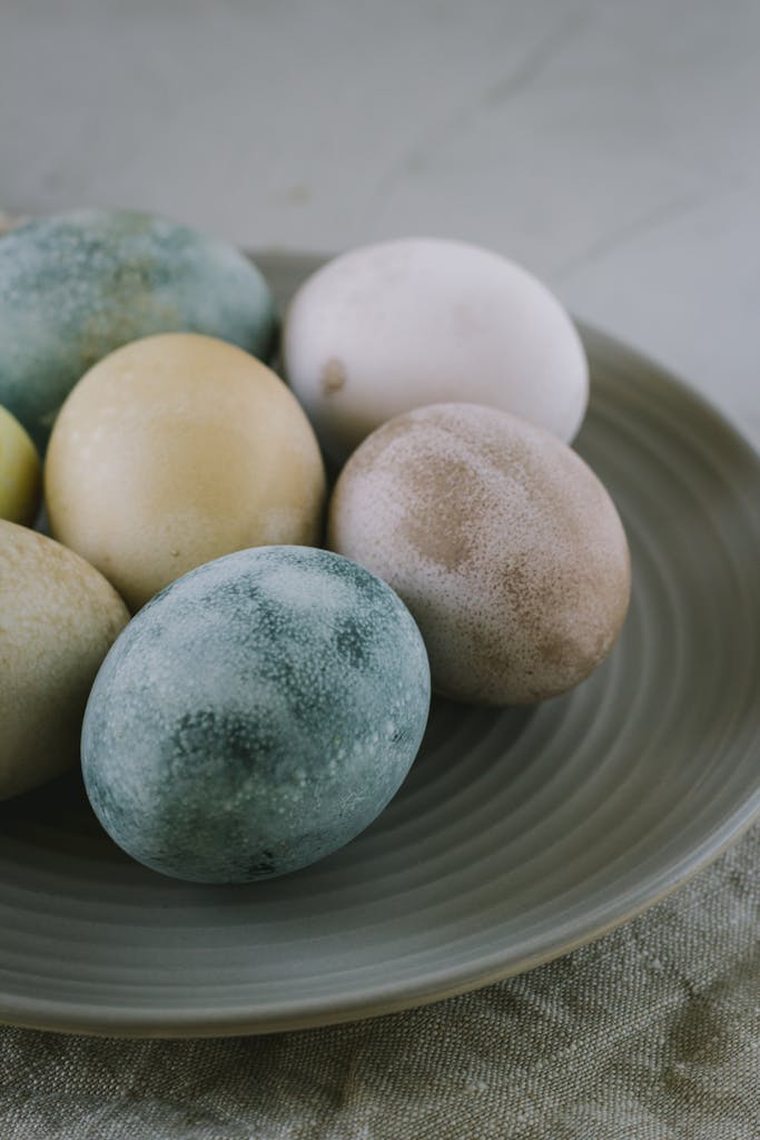 A close-up of naturally painted Easter eggs on a rustic ceramic plate, ideal for festive decorations.